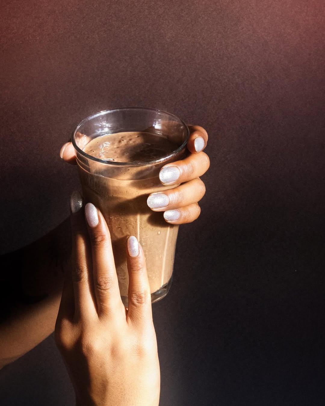 Woman holding a glass with a roots protein shake.